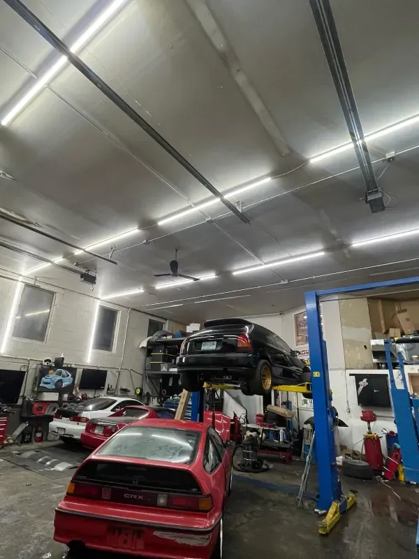 A red car is on a lift in a garage.