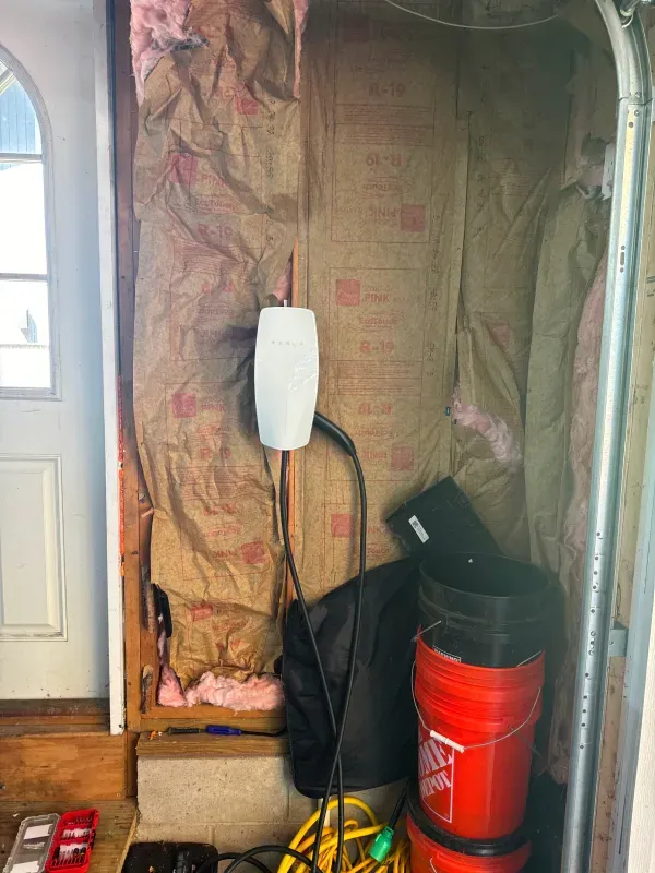 A garage door with insulation on the wall and buckets stacked on top of each other.