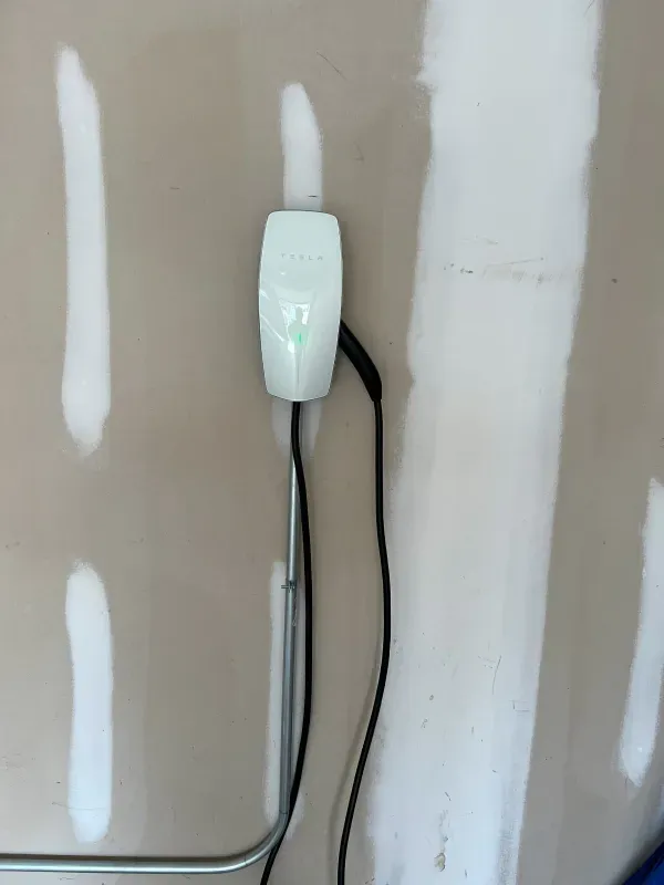 A white box with a green light on it is plugged into a wall.