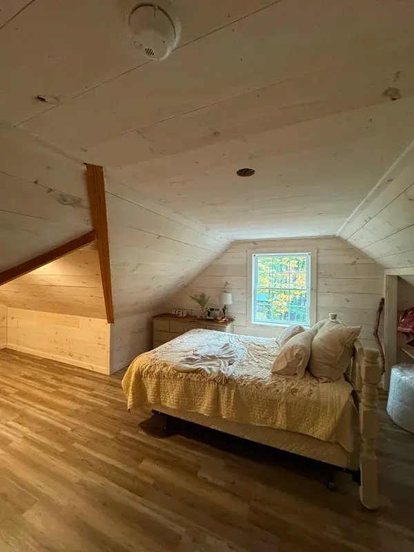 A bedroom with a bed and a window in the attic.