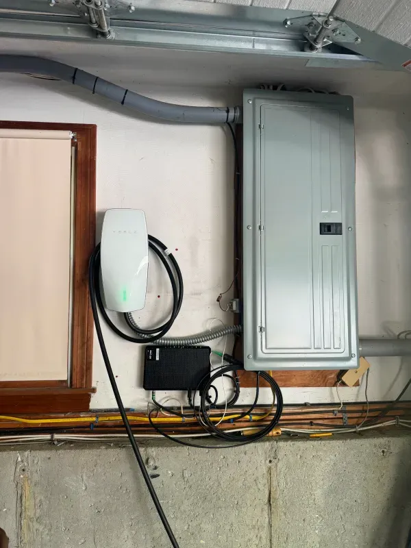 A tesla charging station is attached to a wall next to a window.