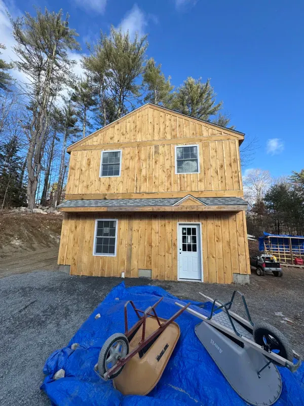 A wheelbarrow is sitting on a blue tarp in front of a house under construction.