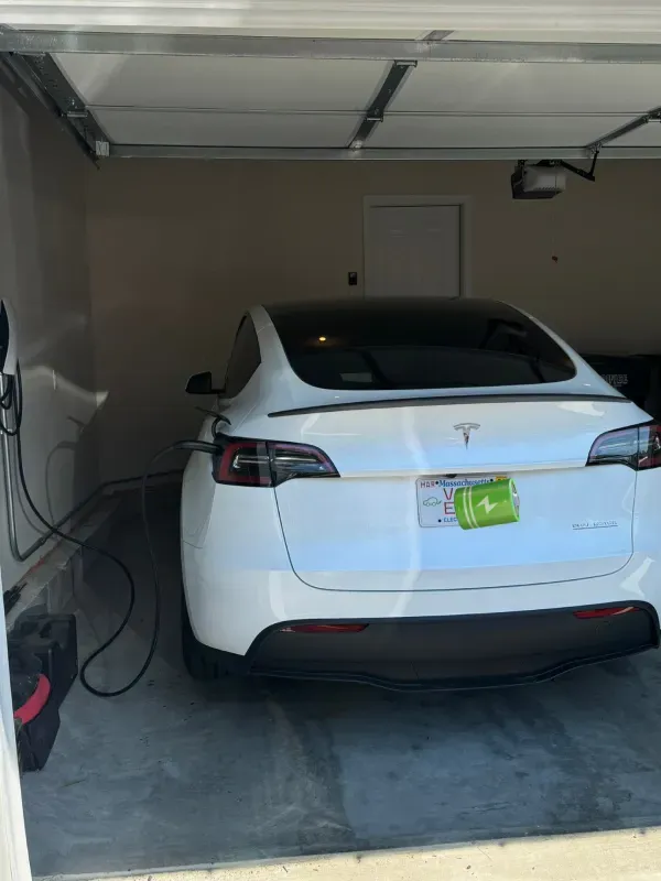 A white tesla model s is charging in a garage.