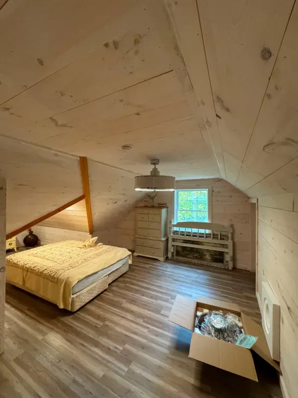 A bedroom with a bed and a box on the floor.