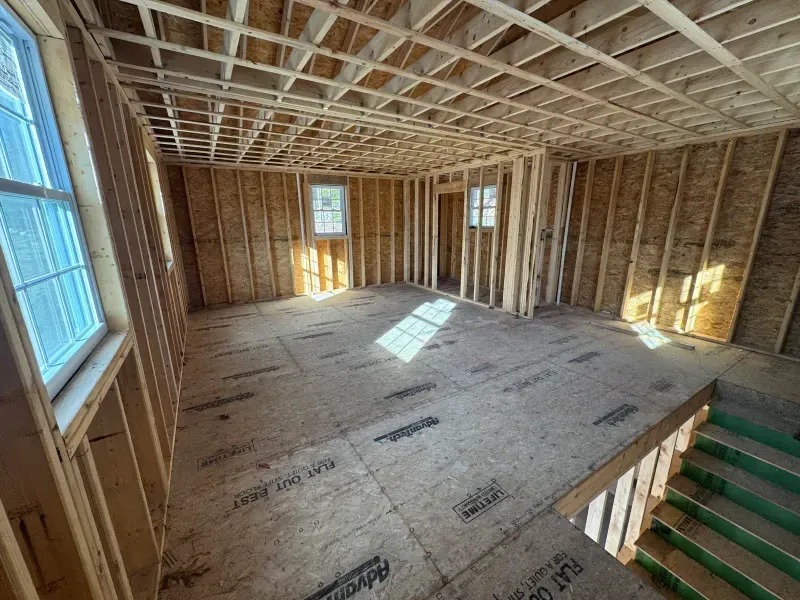 A room in a house under construction with wooden beams and windows.
