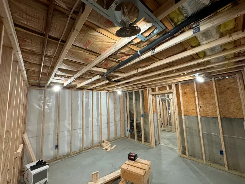 A basement under construction with wooden beams and pipes.