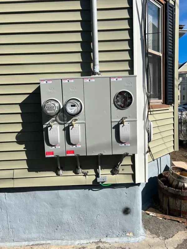 A large electrical box is attached to the side of a house.