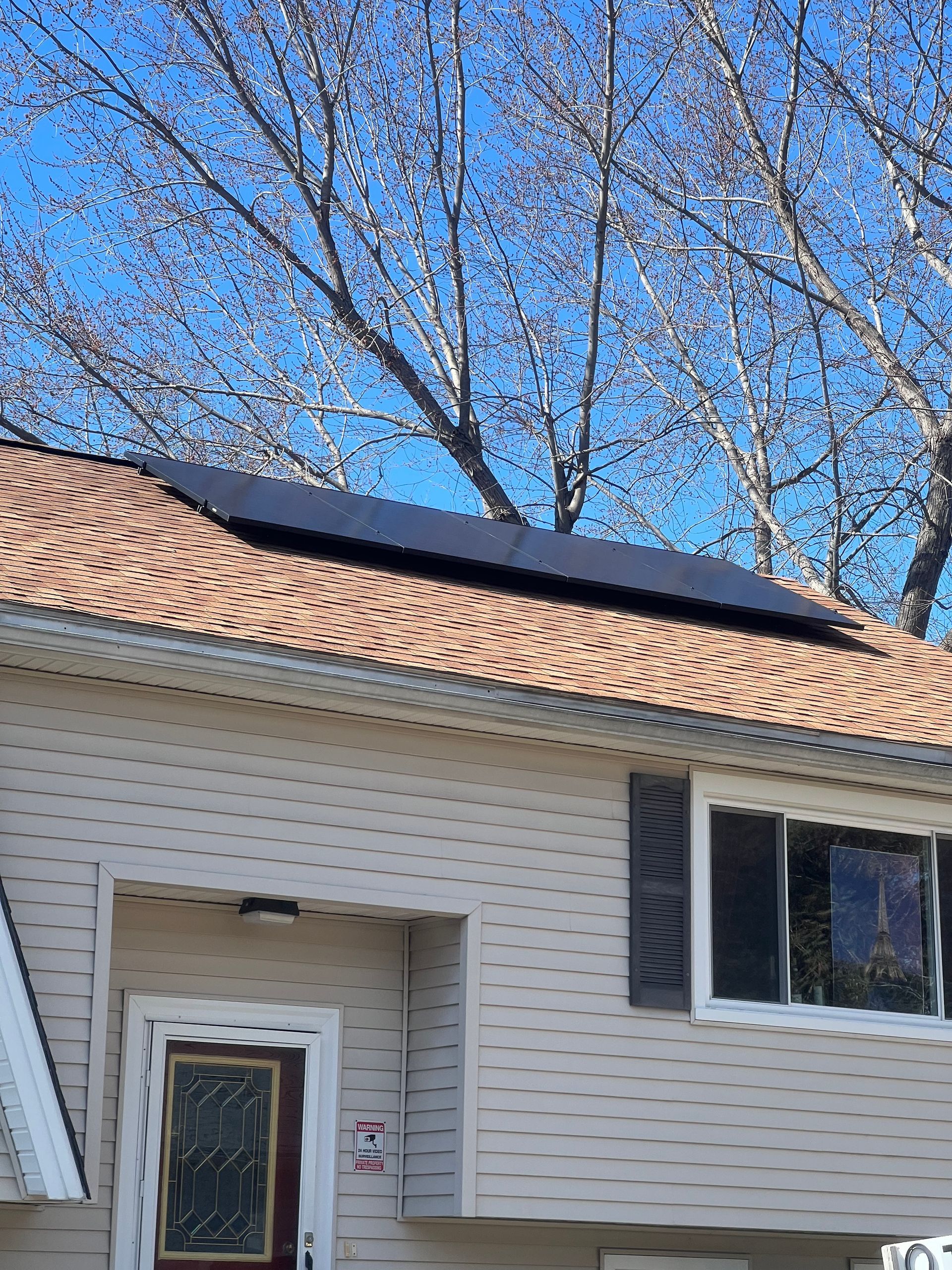 A house with solar panels on the roof and trees in the background.