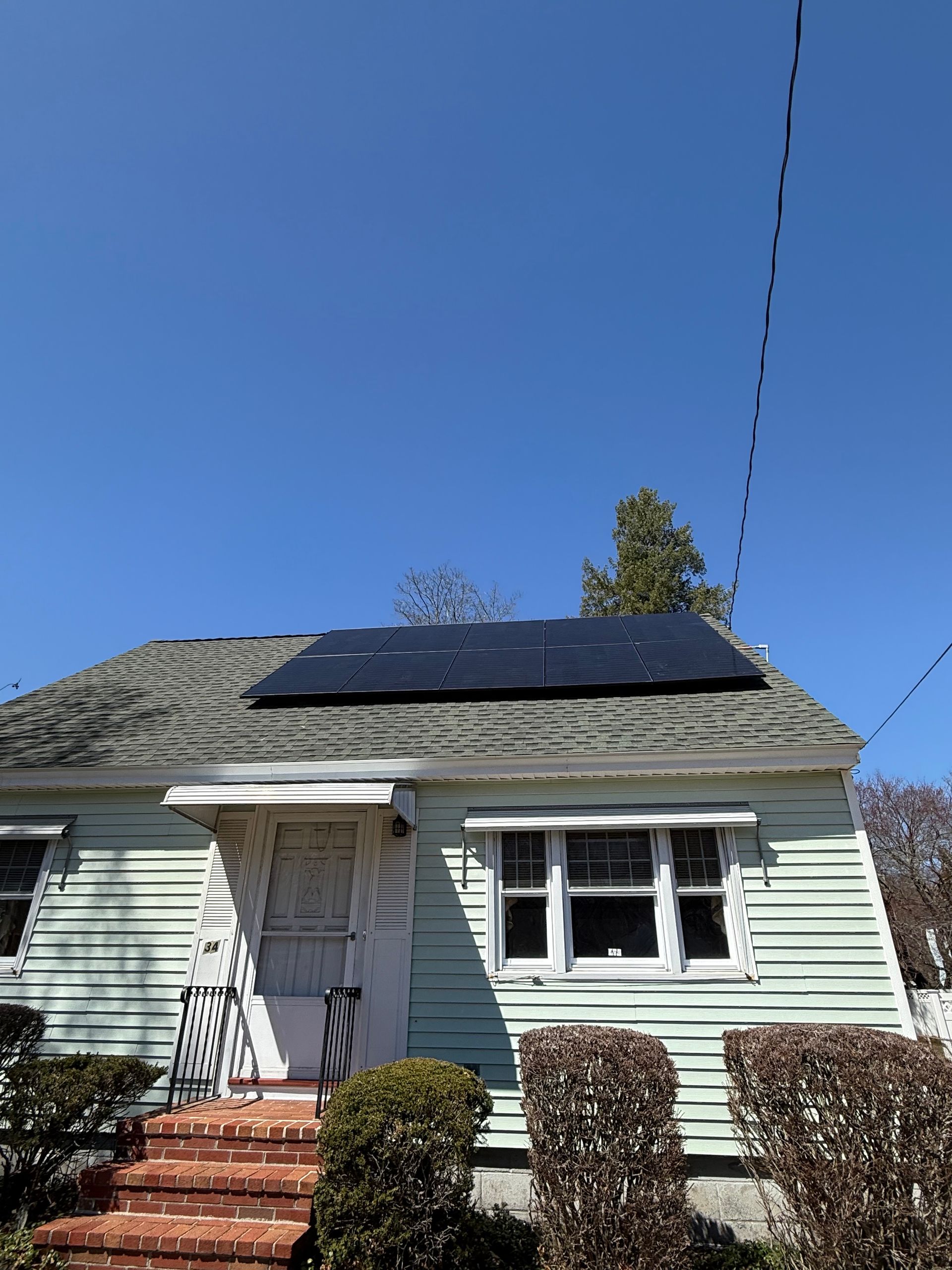 A green house with solar panels on the roof.