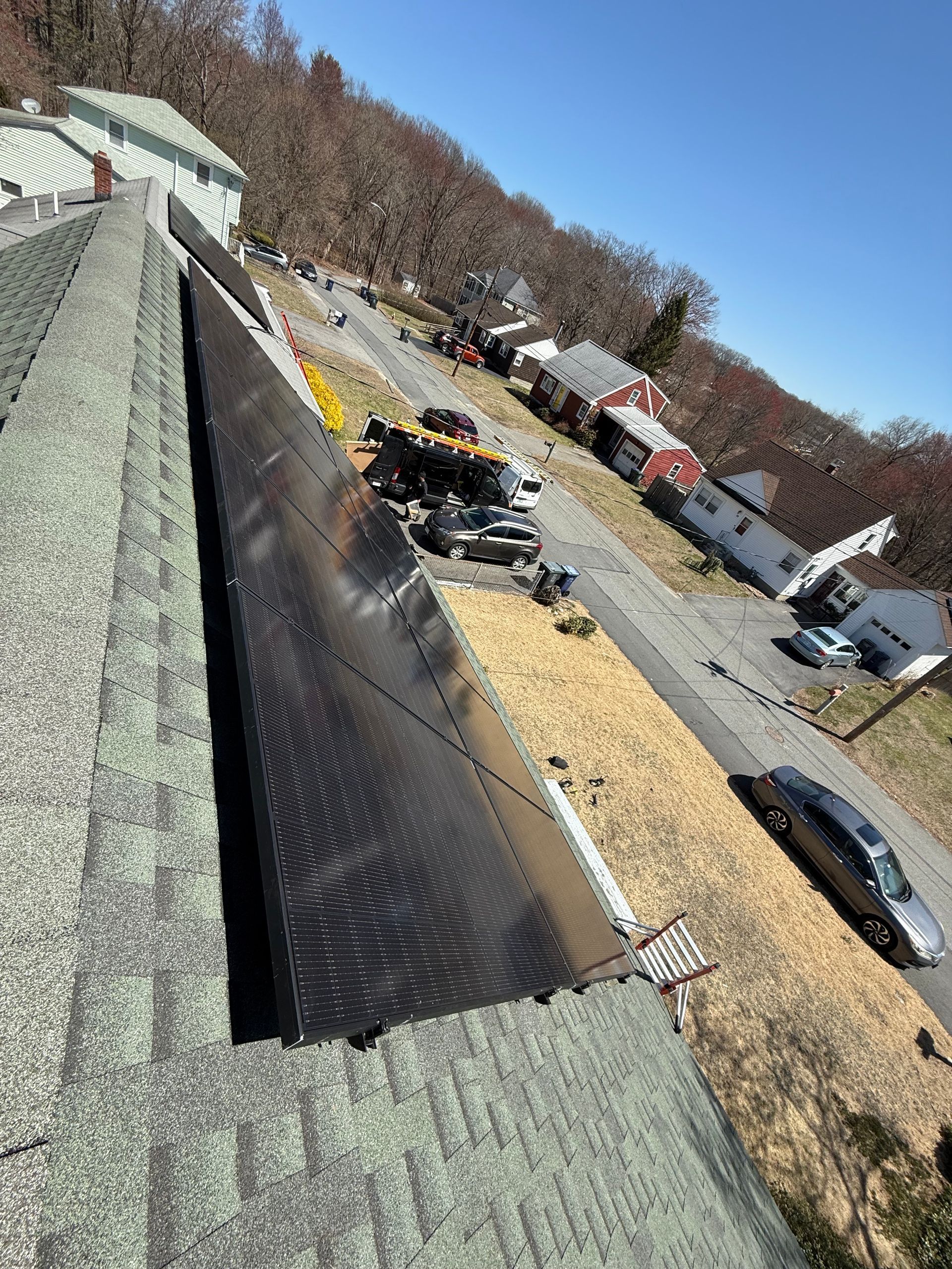 A roof with a lot of shingles on it and a car parked on the side of the road.