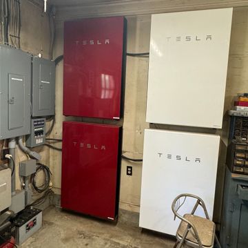 A room with three tesla batteries stacked on top of each other.