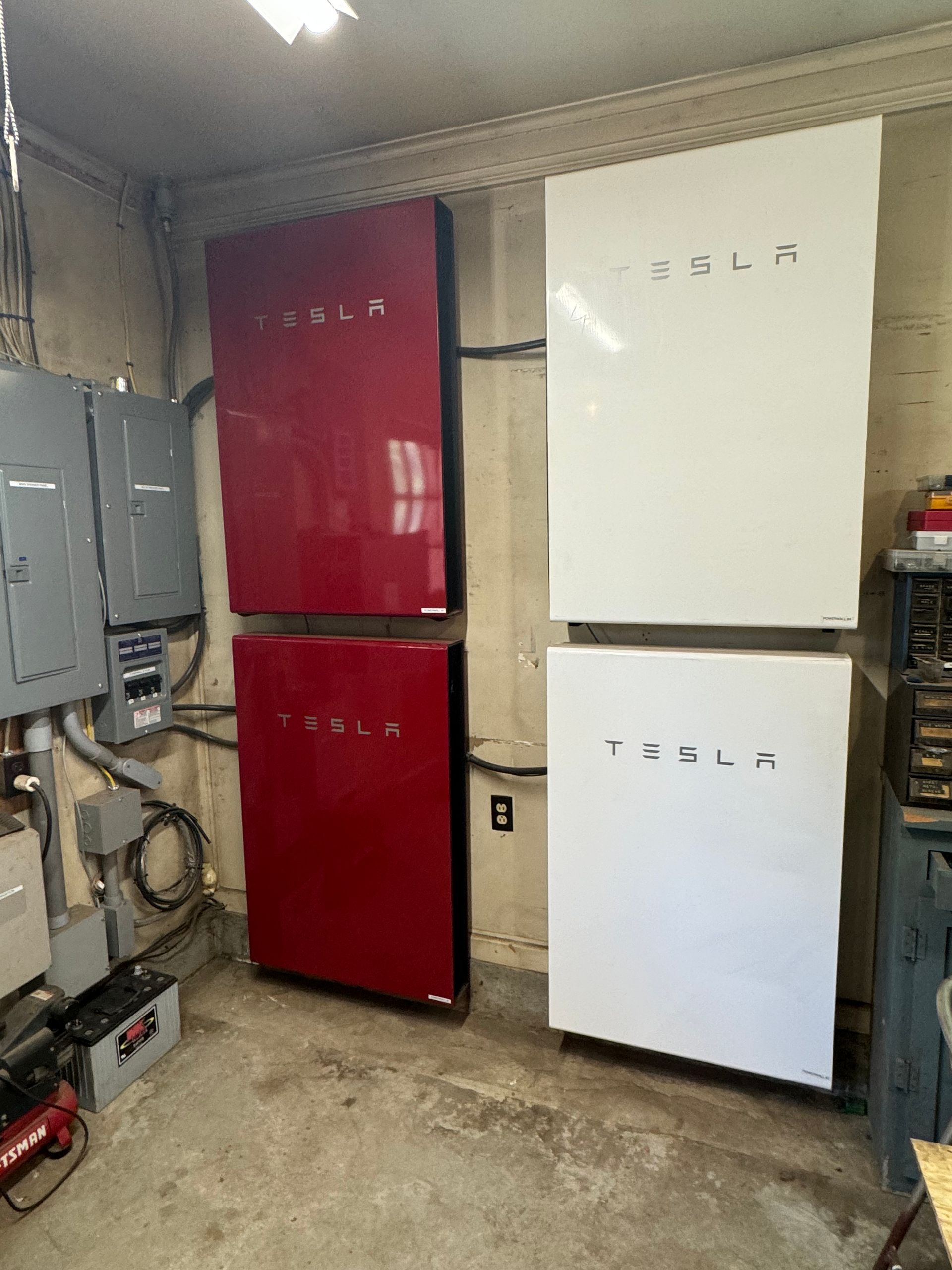 Two tesla solar panels are stacked on top of each other in a garage.