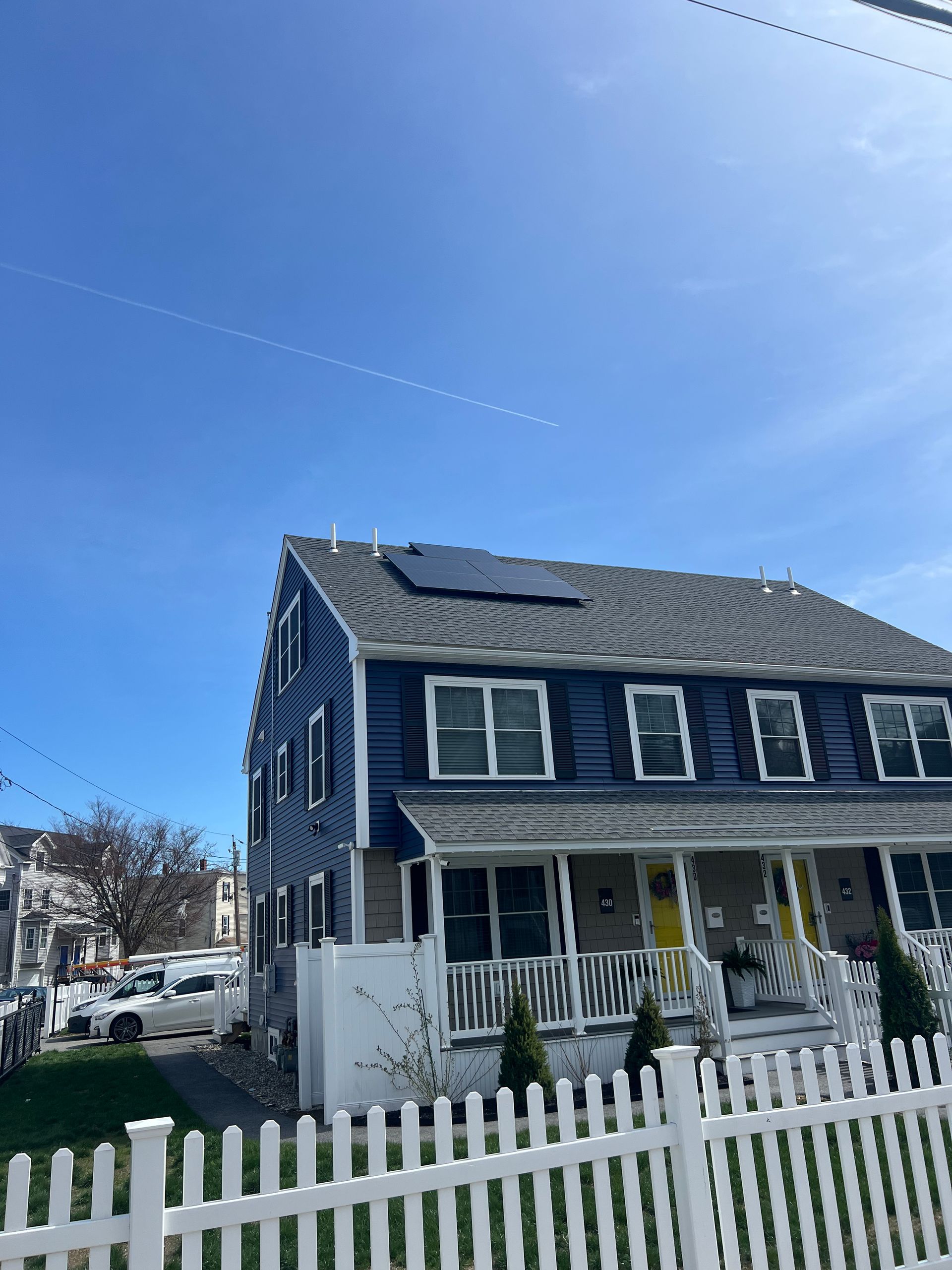 A house with a white picket fence and solar panels on the roof.