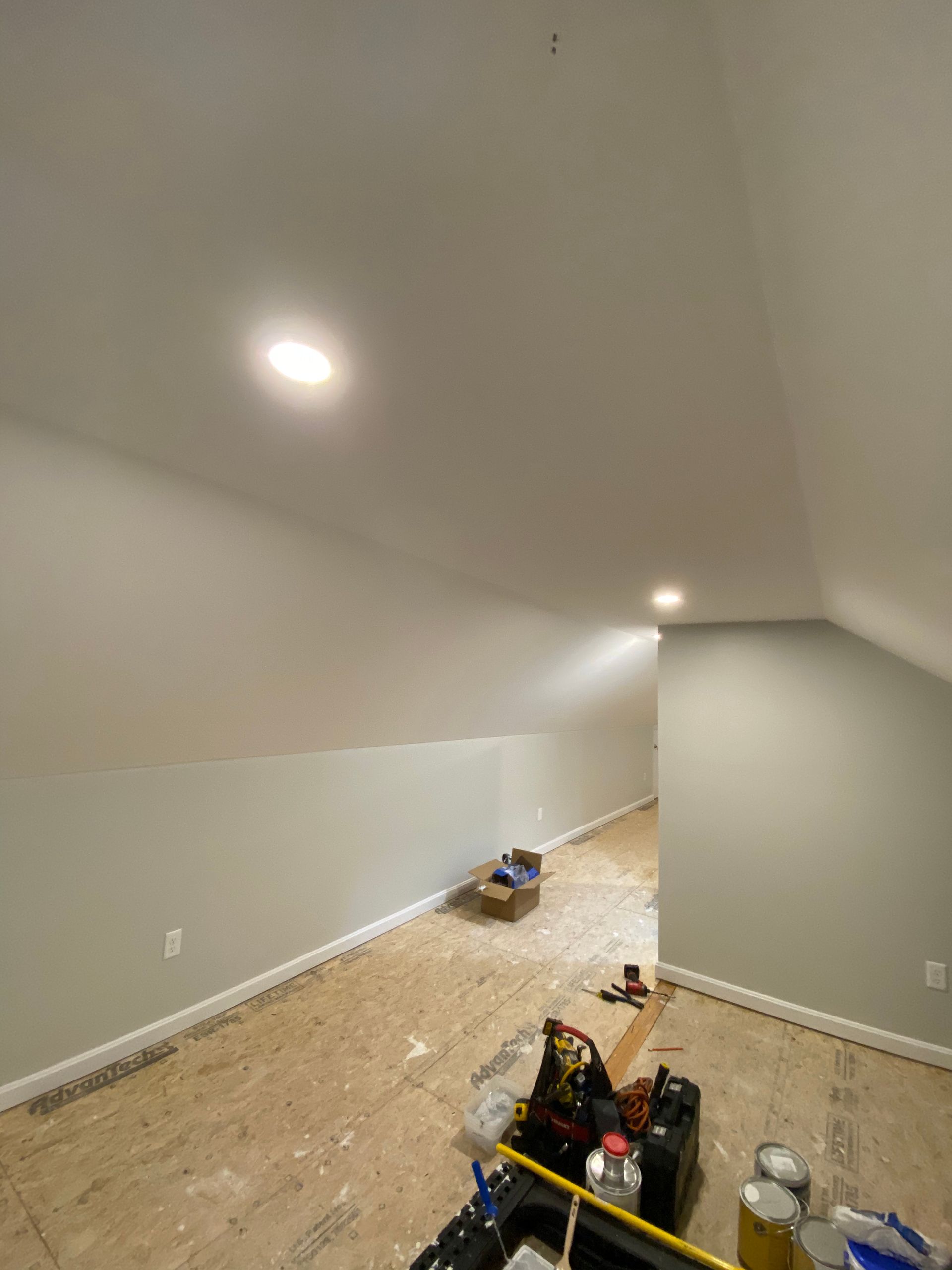 A room with a vaulted ceiling and a lot of tools on the floor.