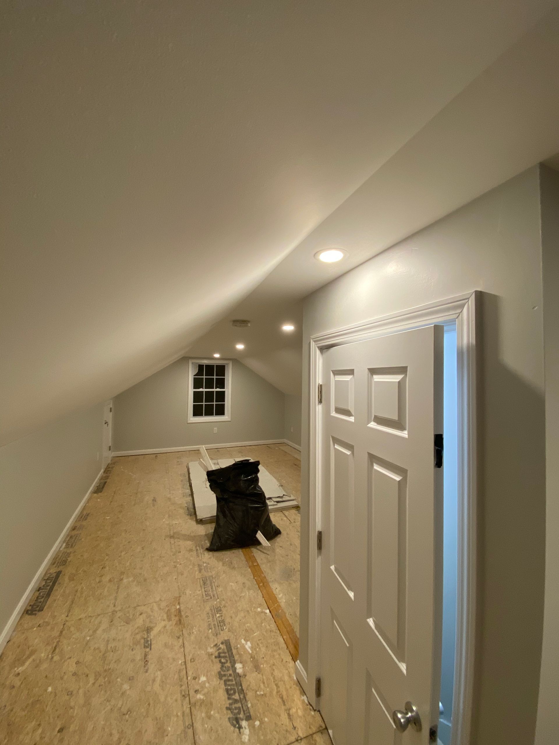 A room with a ceiling that is very high and a door that is open.