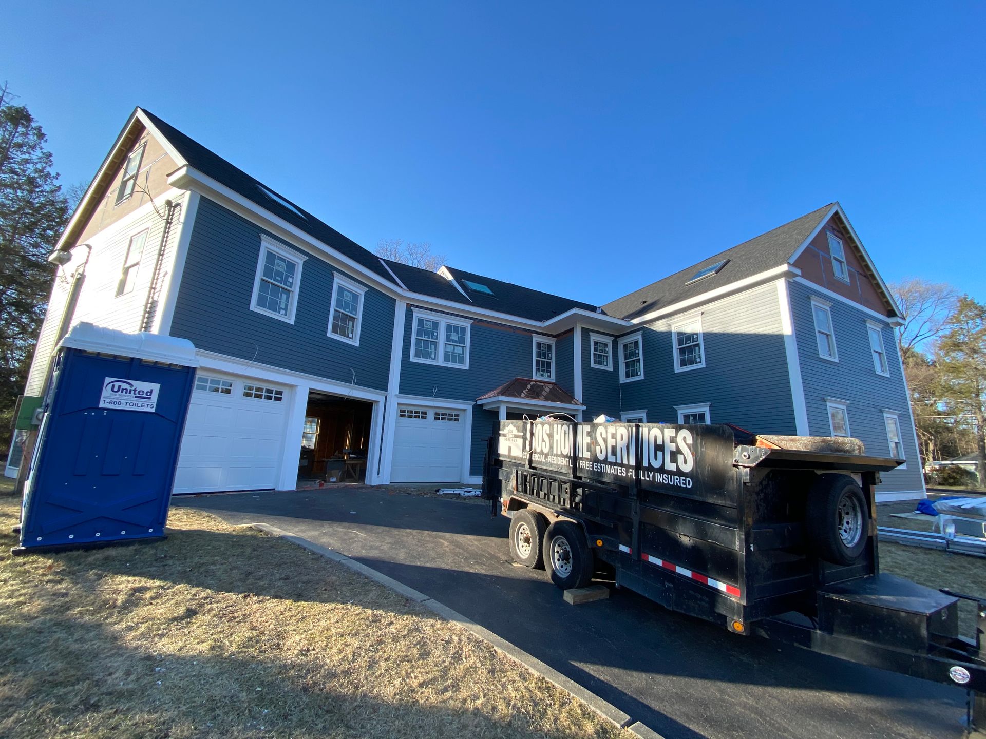 A dumpster is parked in front of a large house.