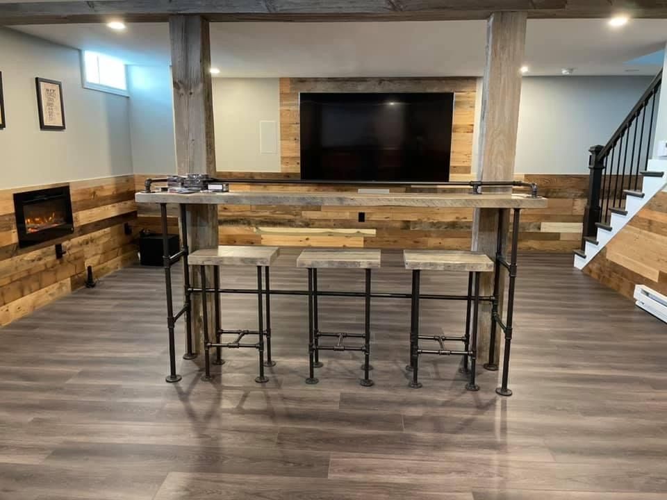 A basement with a table and stools and a flat screen tv.