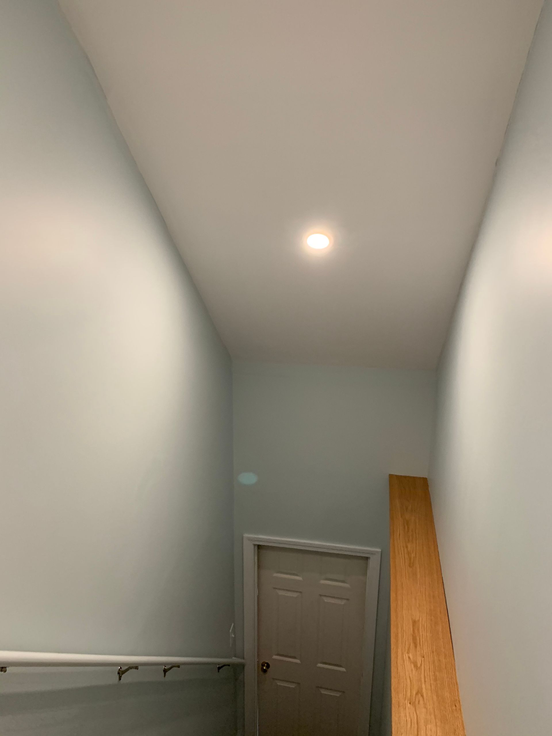 A hallway with a door and a light on the ceiling.