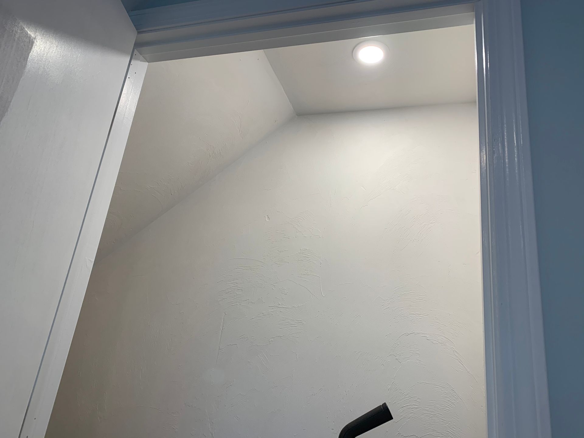 A closet with a light on the ceiling and a door open.