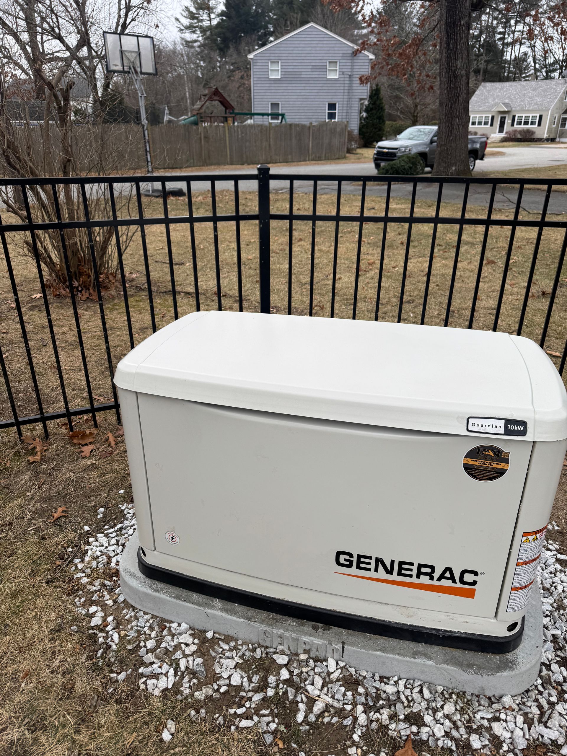 A generator is sitting in the grass next to a fence.