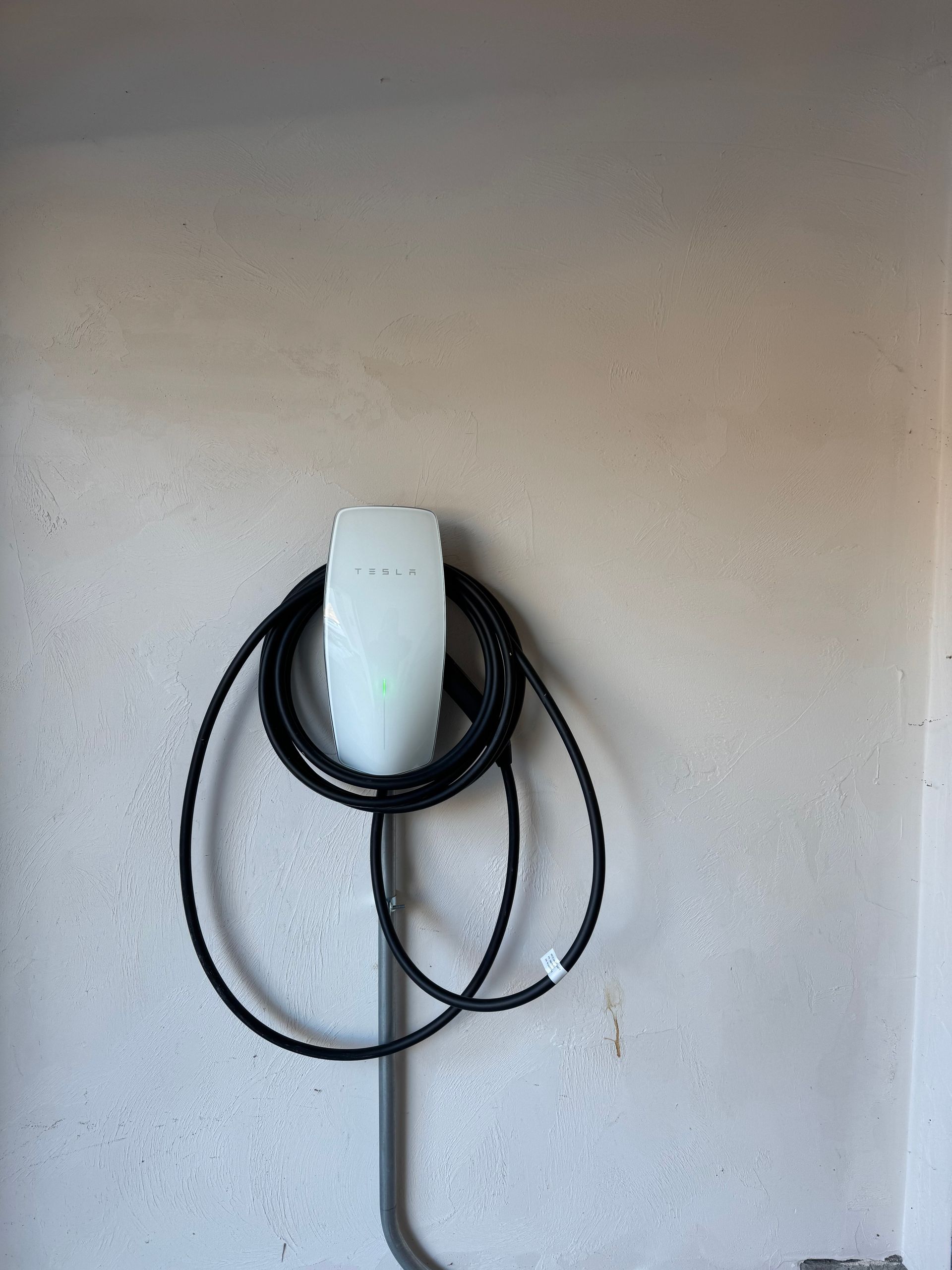 A tesla charging station is hanging on a wall.