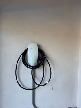 A tesla charging station is hanging on a wall.