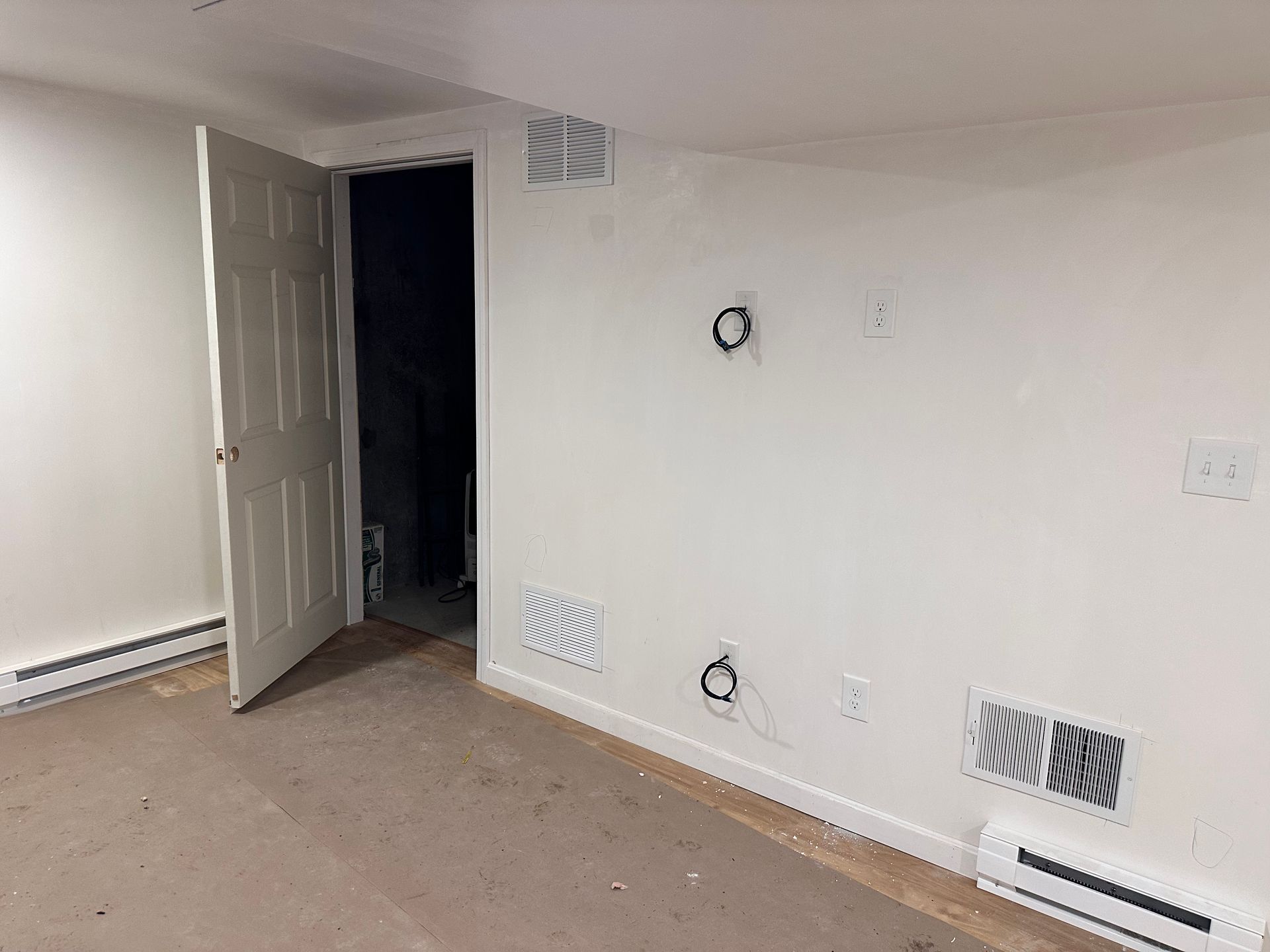 An empty room with a door open and a carpeted floor.