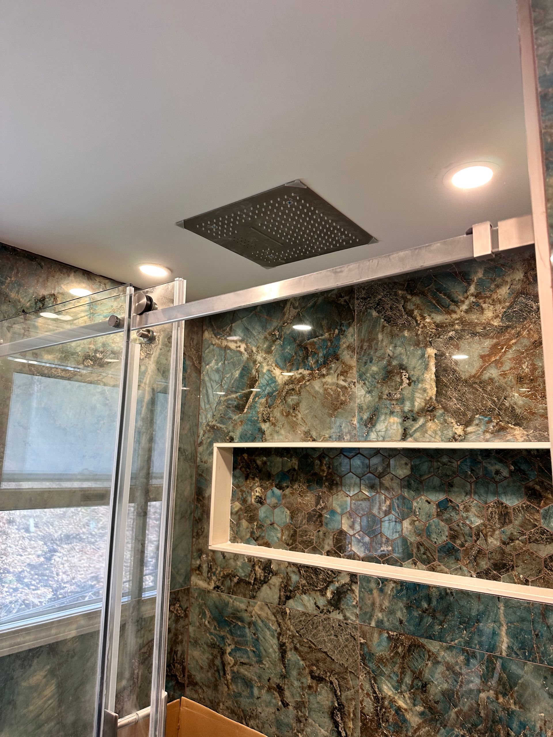 A bathroom with a shower head and a shelf.