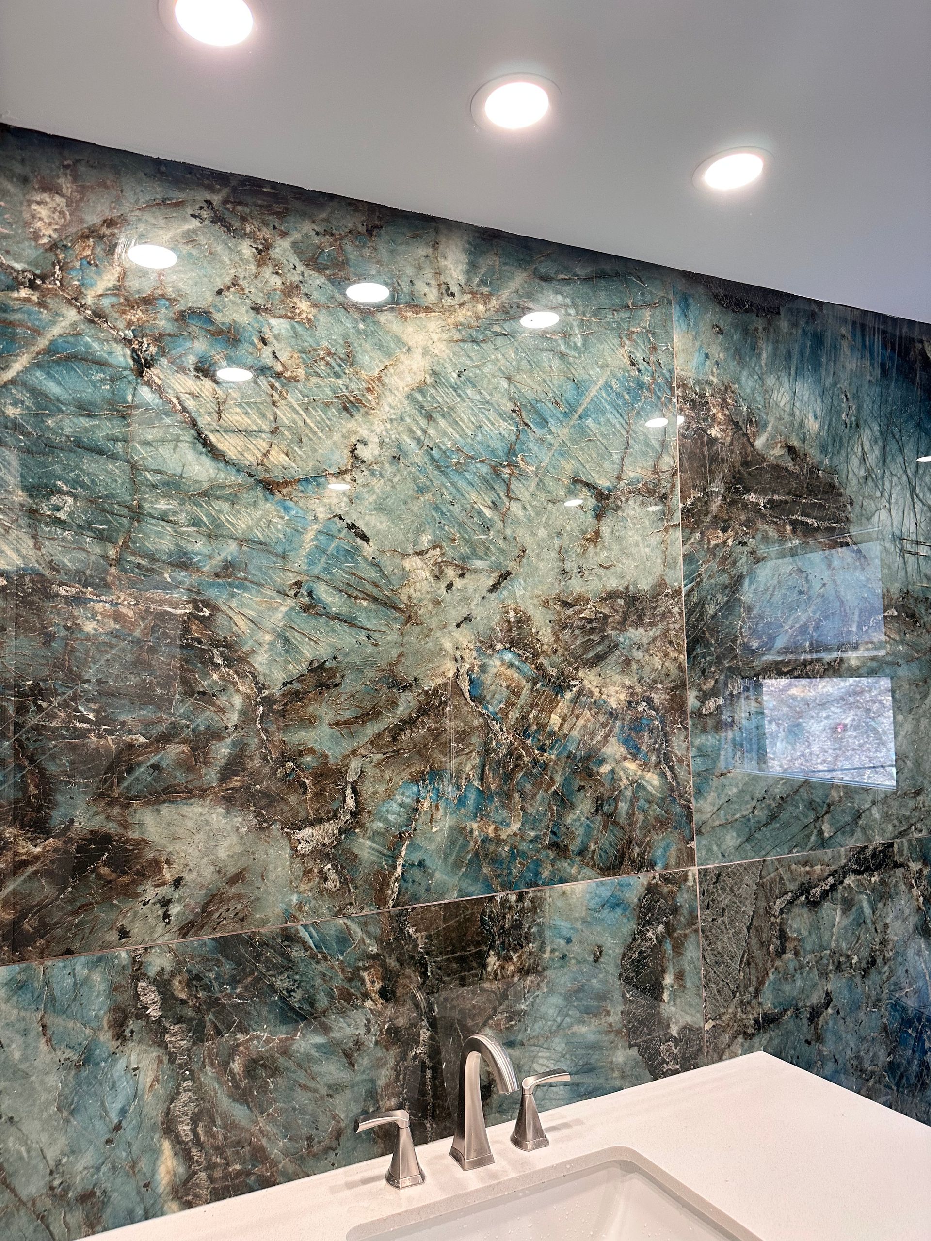 A bathroom with a blue marble wall and a sink.