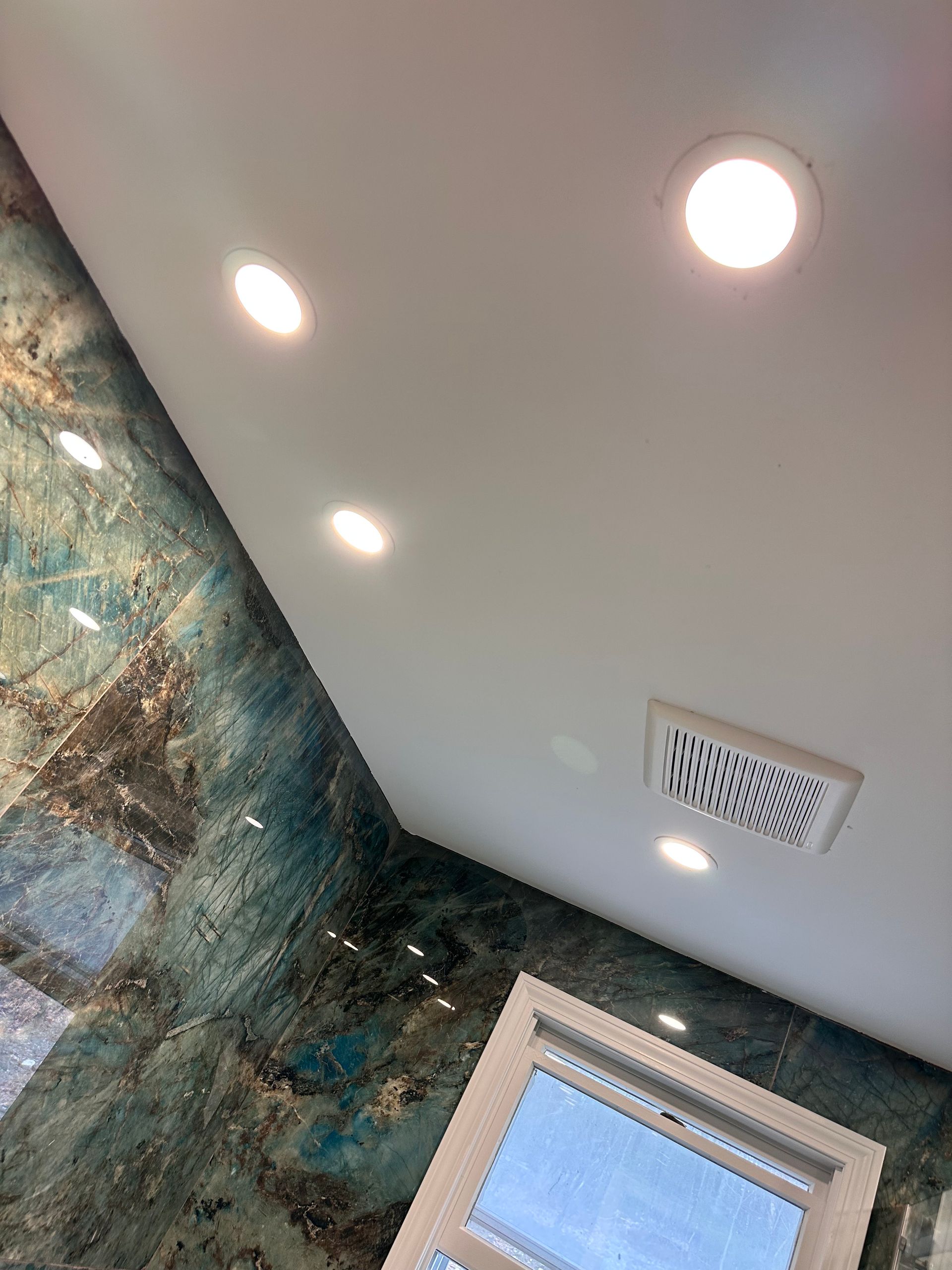 A bathroom with a ceiling fan and a window.