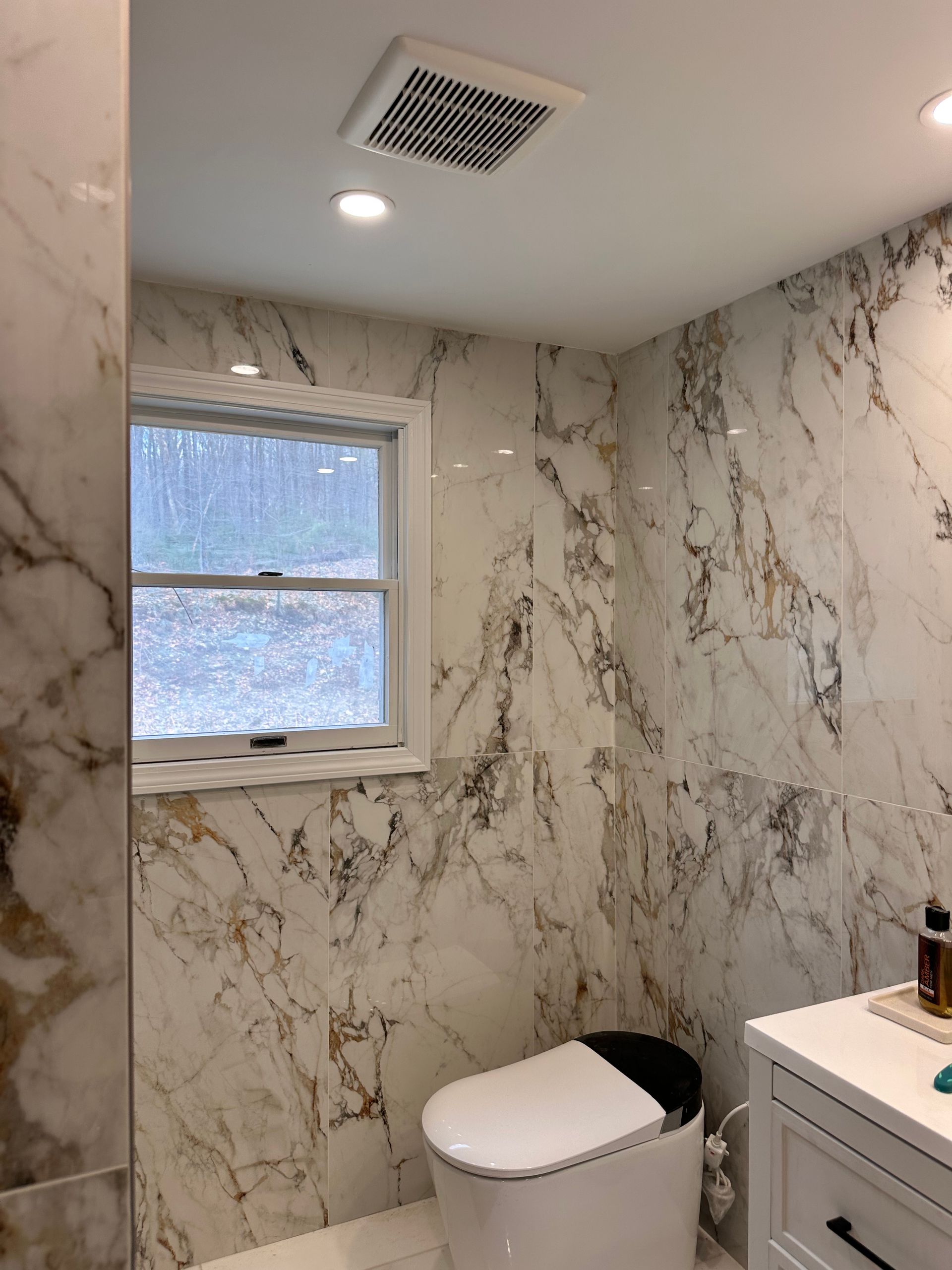 A bathroom with marble walls and a toilet