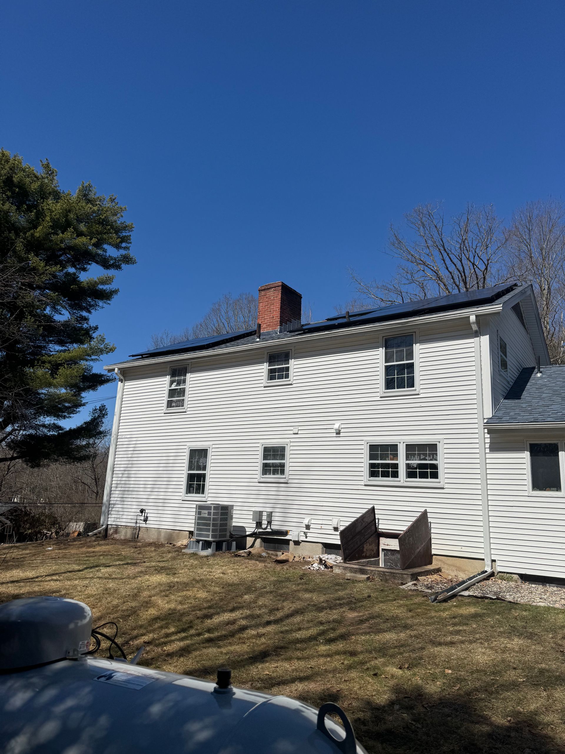 A white house with a chimney on the roof and a jeep parked in front of it.