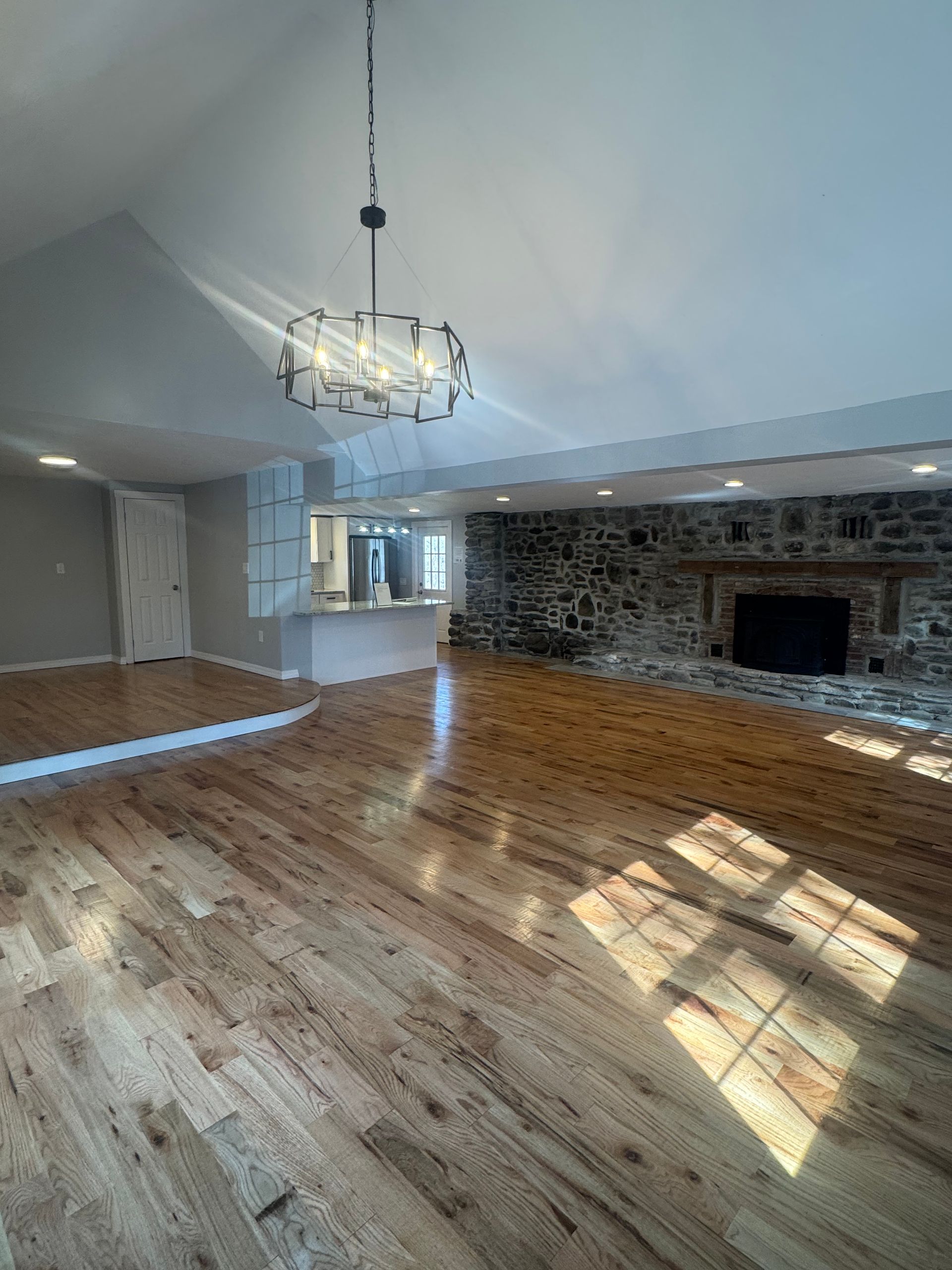 An empty living room with hardwood floors and a fireplace.