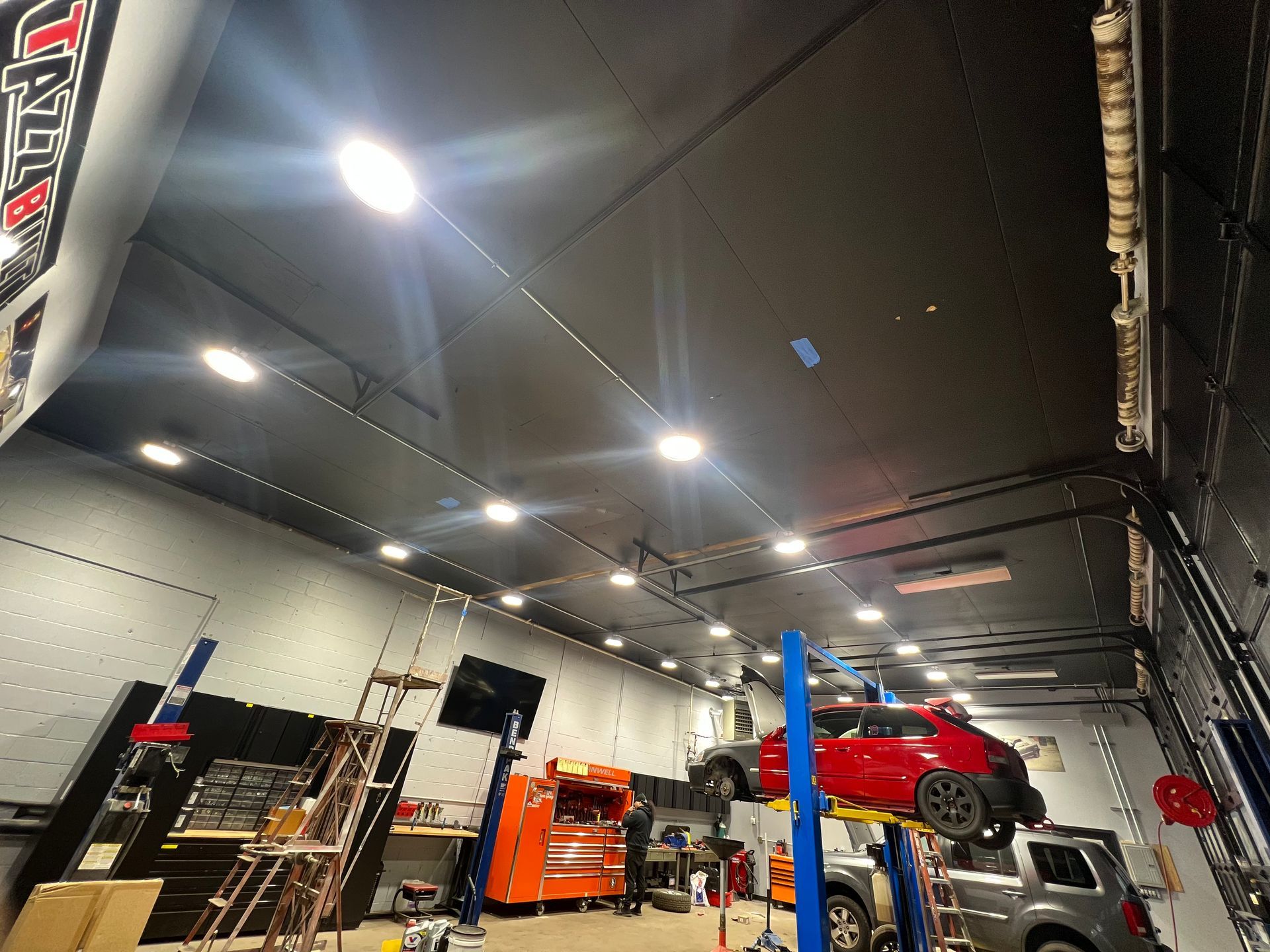 A red car is on a lift in a garage.