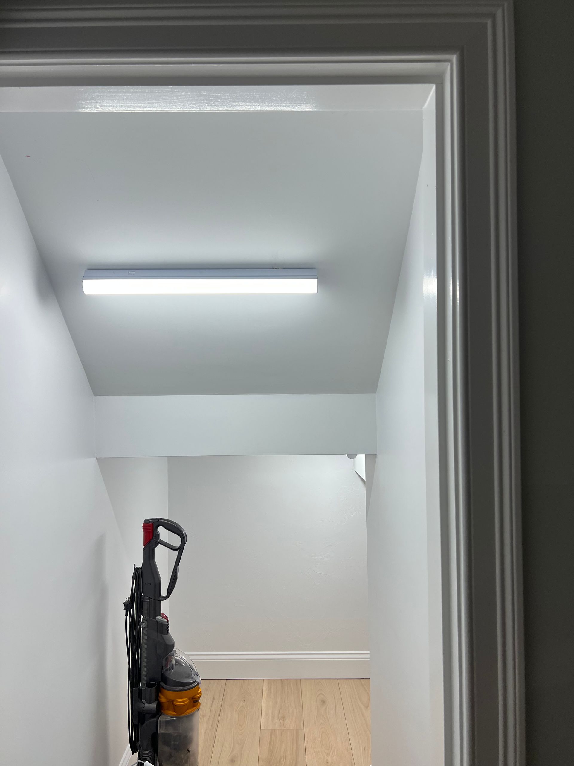 A vacuum cleaner is hanging from the ceiling in a hallway.