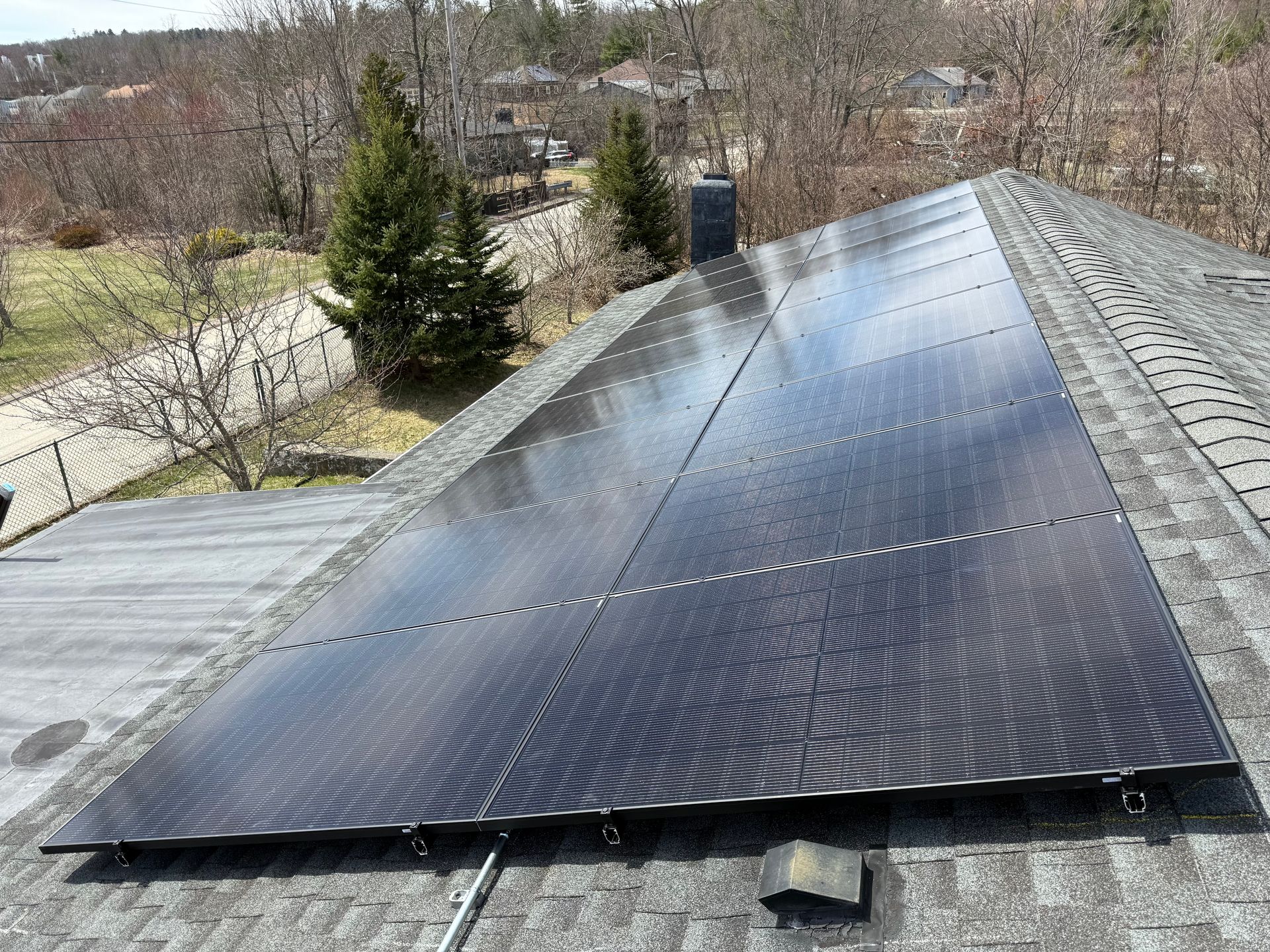 There are many solar panels on the roof of a house.