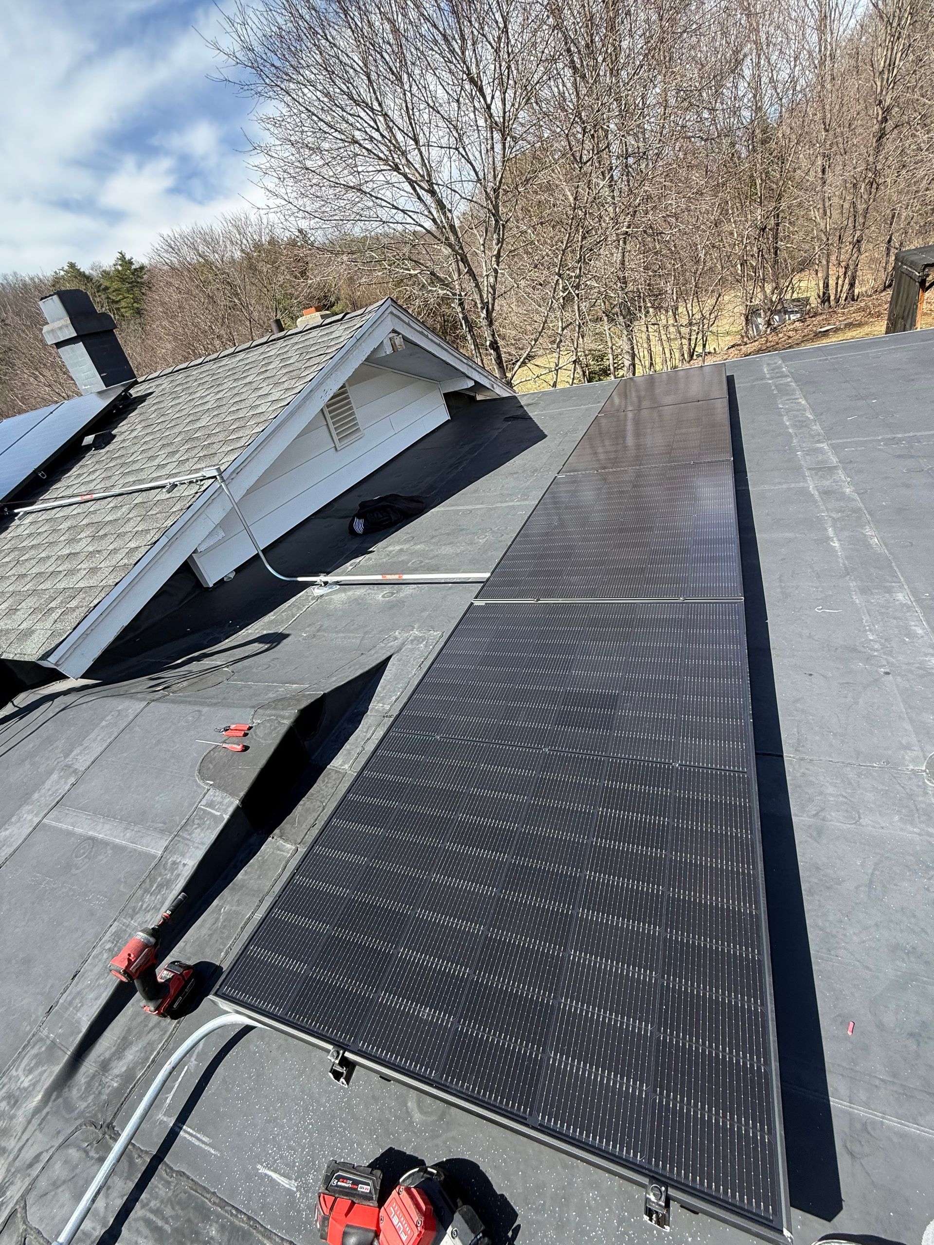 A person is installing solar panels on the roof of a house.