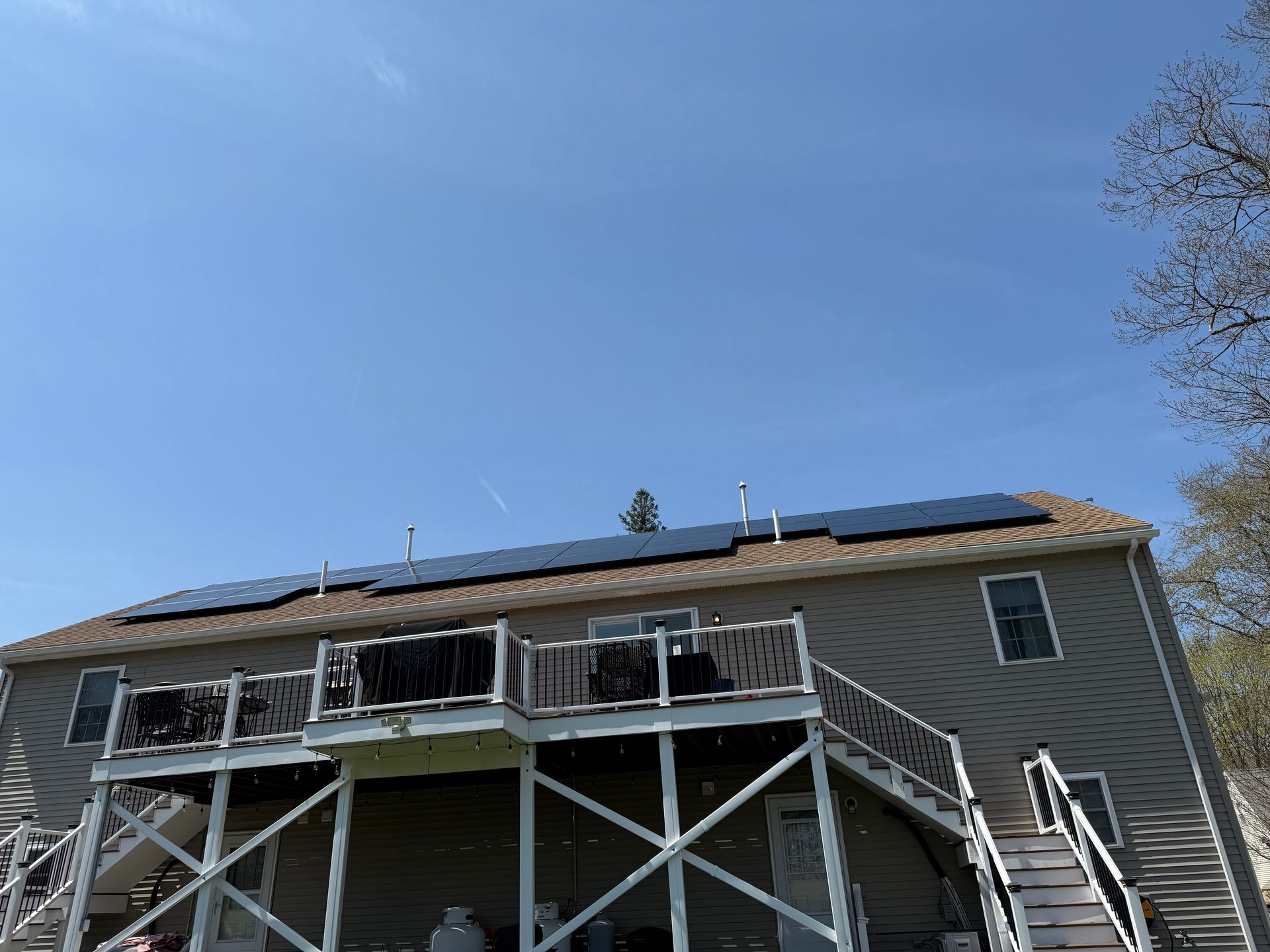 A house with a deck and solar panels on the roof.