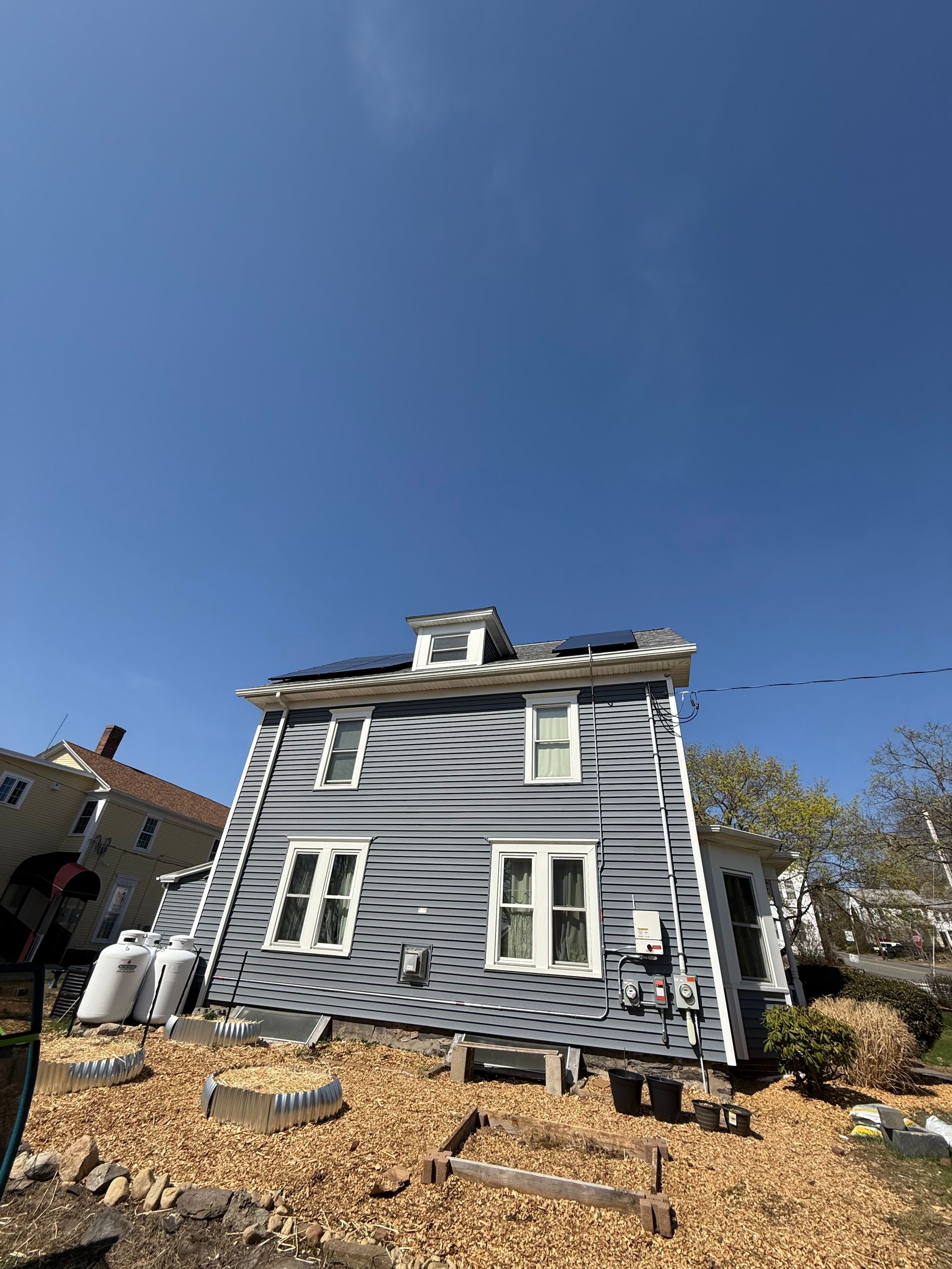 A man is standing in front of a house that is leaning over.