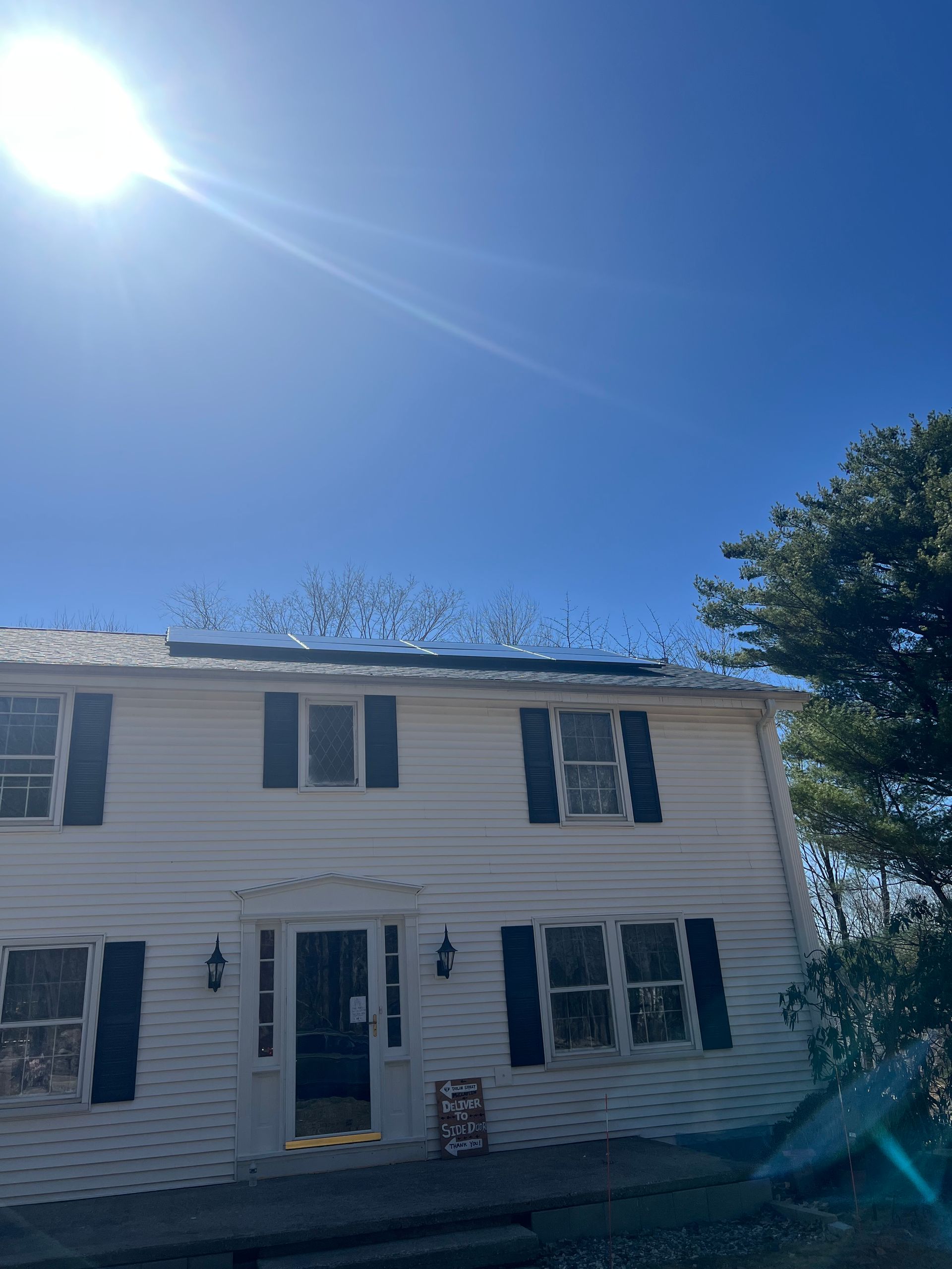 A white house with black shutters and a blue sky in the background.