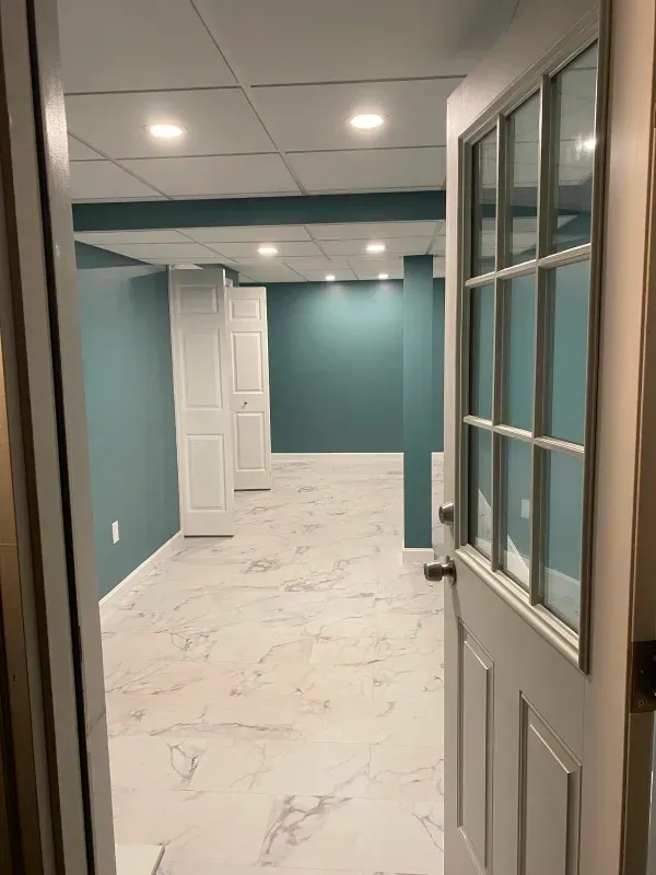 An empty basement with blue walls and white tile floors.