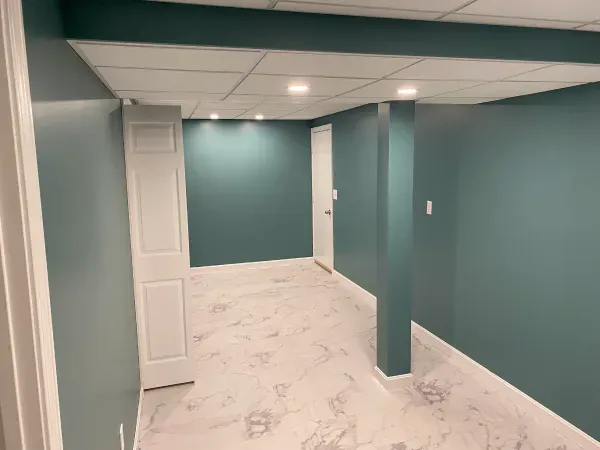 An empty basement with blue walls and white floors.