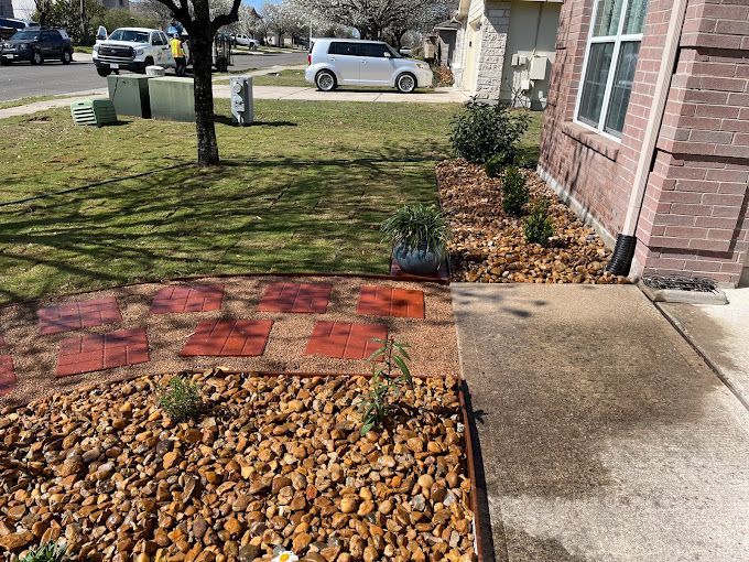 A brick walkway leading to a house with a gravel bed in front of it.