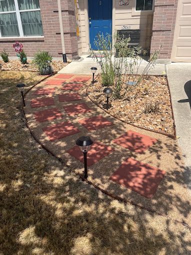 A sidewalk with lights on it in front of a house.