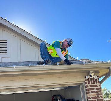 A man is kneeling on the roof of a house.