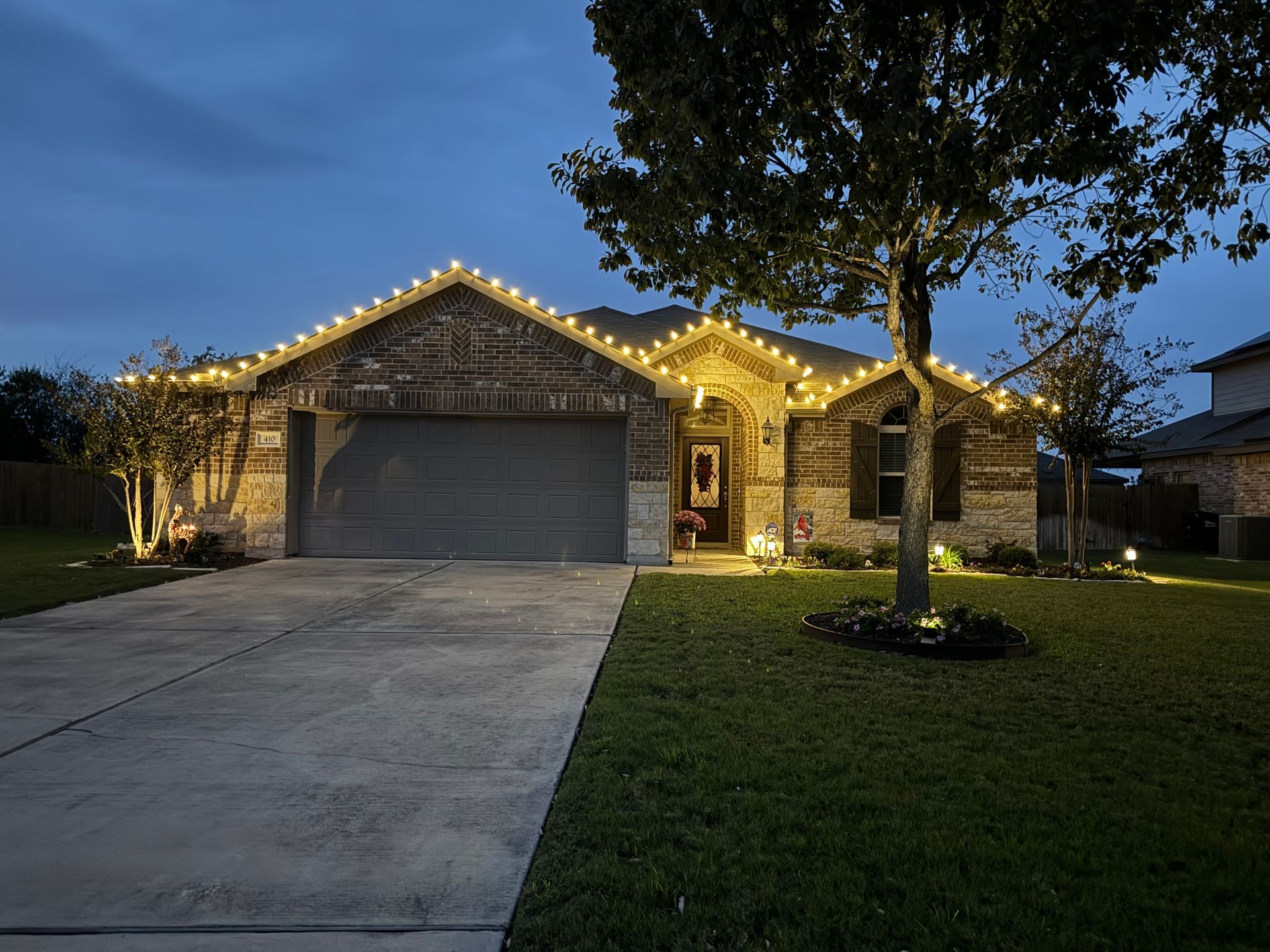 A house with christmas lights on the roof is lit up at night