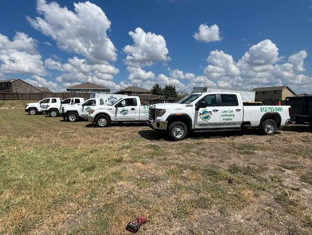 A row of trucks are parked in a grassy field.
