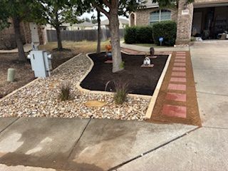 Front yard landscaping with rock bed, mulch, stepping stones, and a small tree.