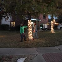 Two men are standing in front of a house decorated with christmas lights.