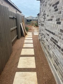 A walkway between two houses with brick walls and a wooden fence.